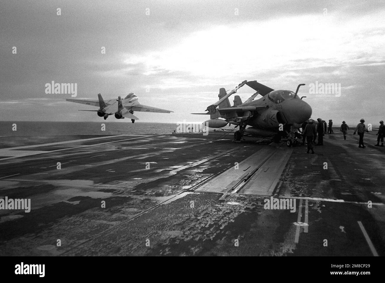 A Fighter Squadron 84 (VF-84) F-14A Tomcat aircraft, left, is launched from one of the waist catapults aboard the nuclear-powered aircraft carrier USS ABRAHAM LINCOLN (CVN-72). An attack squadron 65 (VA-65) A-6E Intruder aircraft is at right. Country: Atlantic Ocean (AOC) Stock Photo