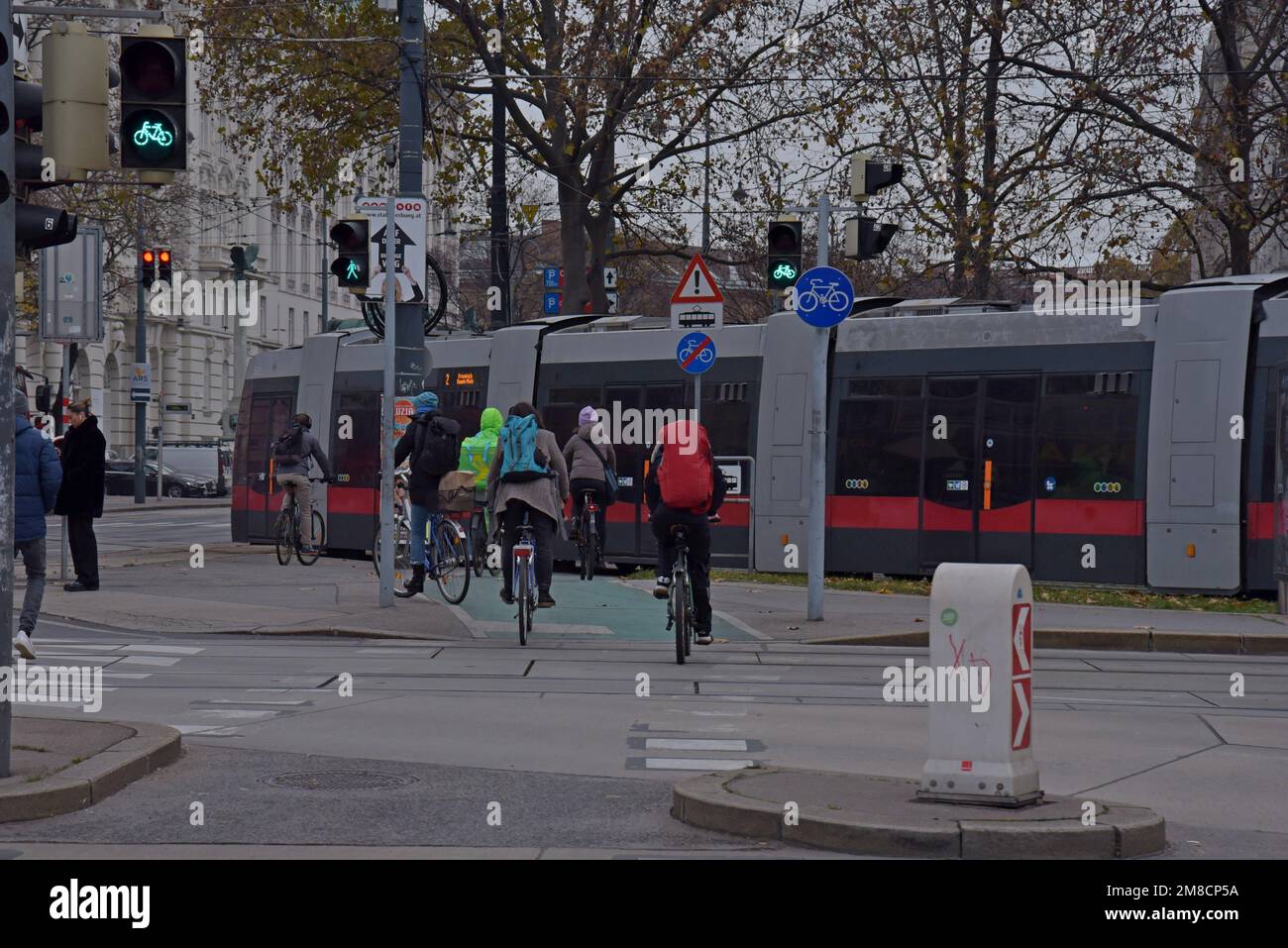 Cyclists waiting at a road junction whilst a tram passes in Vienna, Austria Stock Photo