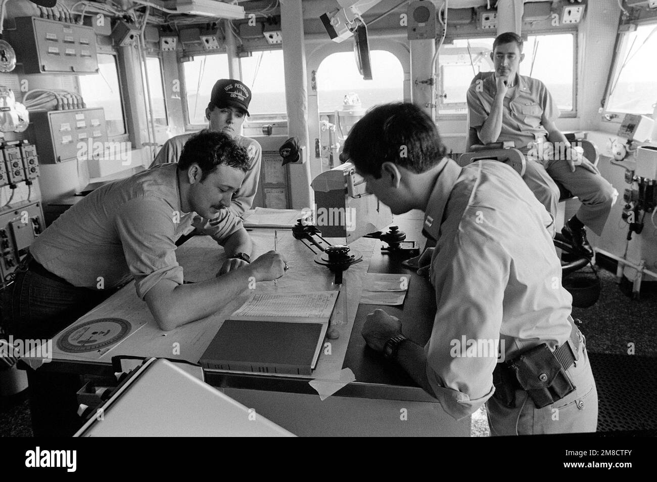 Navy personnel work at the chart table in the pilot house aboard the