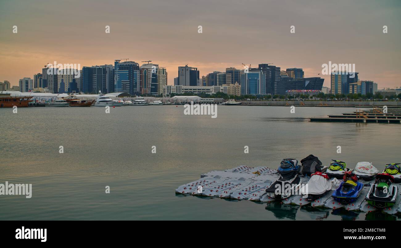 Doha skyline from the box park , Doha Qatar sunset shot with dhows in Arabic gulf and clouds in the sky in background. Stock Photo