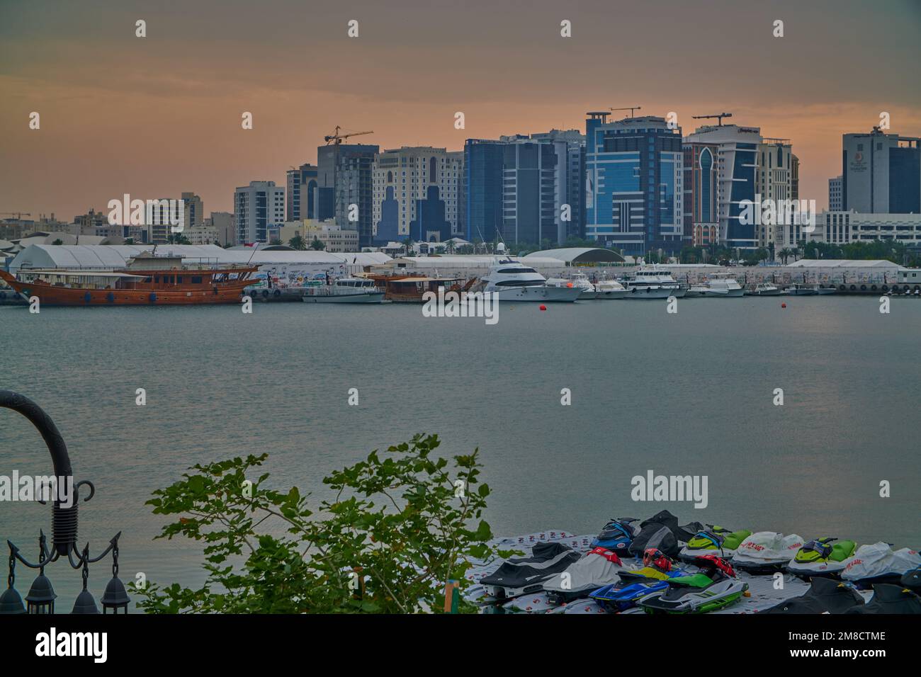 Doha skyline from the box park , Doha Qatar sunset shot with dhows in Arabic gulf and clouds in the sky in background. Stock Photo