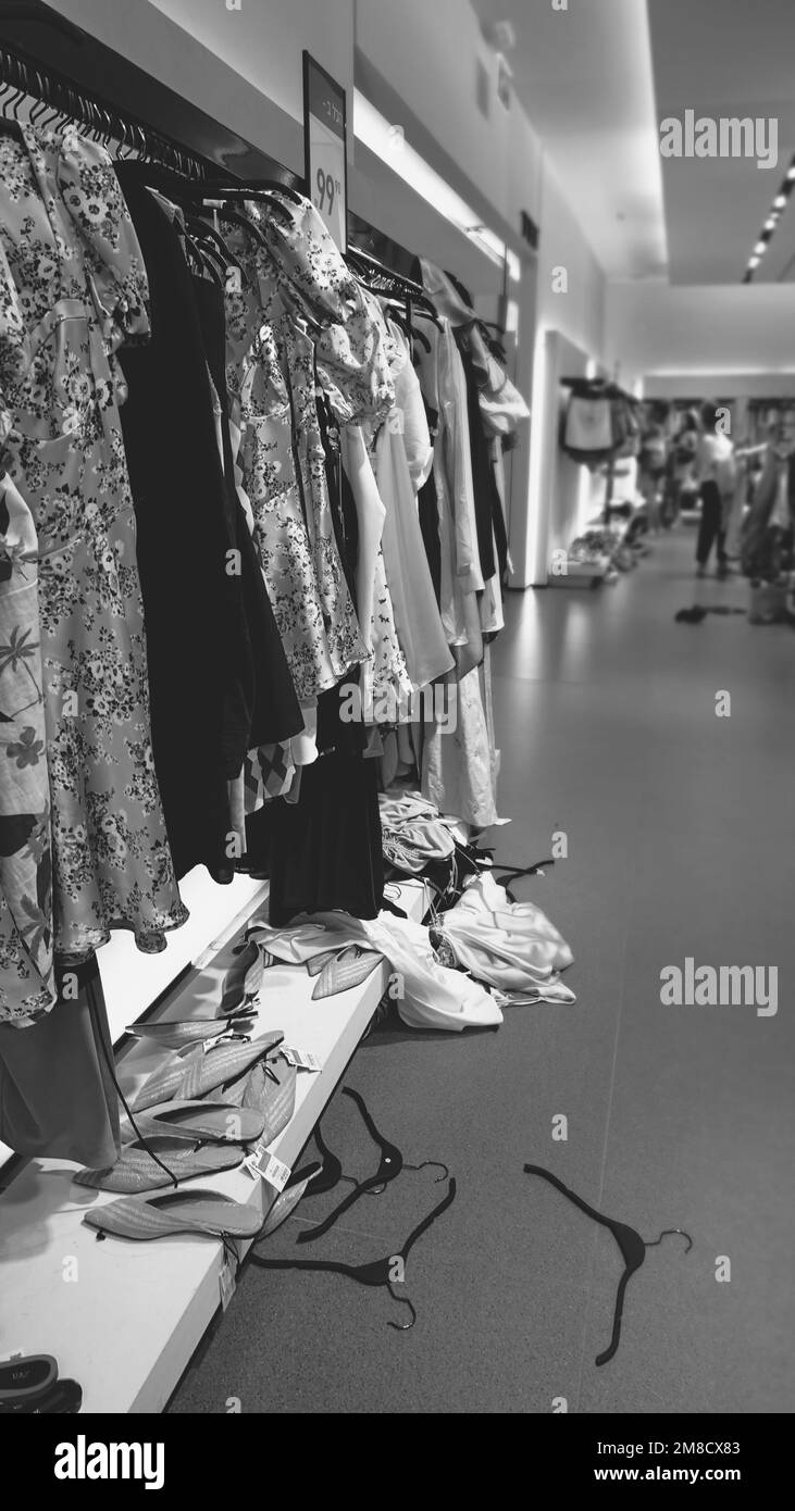 Sale in a clothing store. Clothes and hangers are scattered on the floor. Monochrome Photo Stock Photo