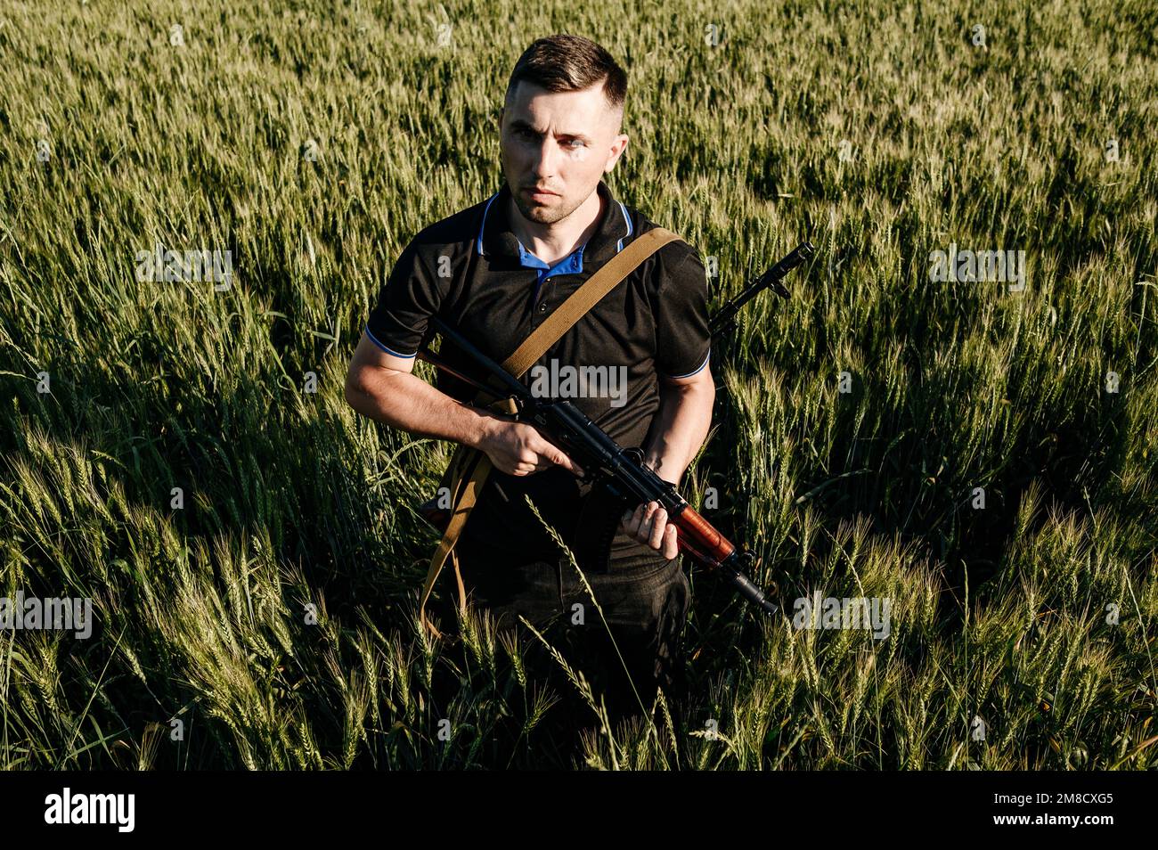 The man in the field with a machine gun, Ukrainian men are preparing for the war, Kalashnikov's automatic rifle. Stock Photo
