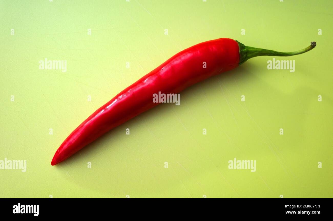 Fresh uncut red pepper on a green cutting board Stock Photo
