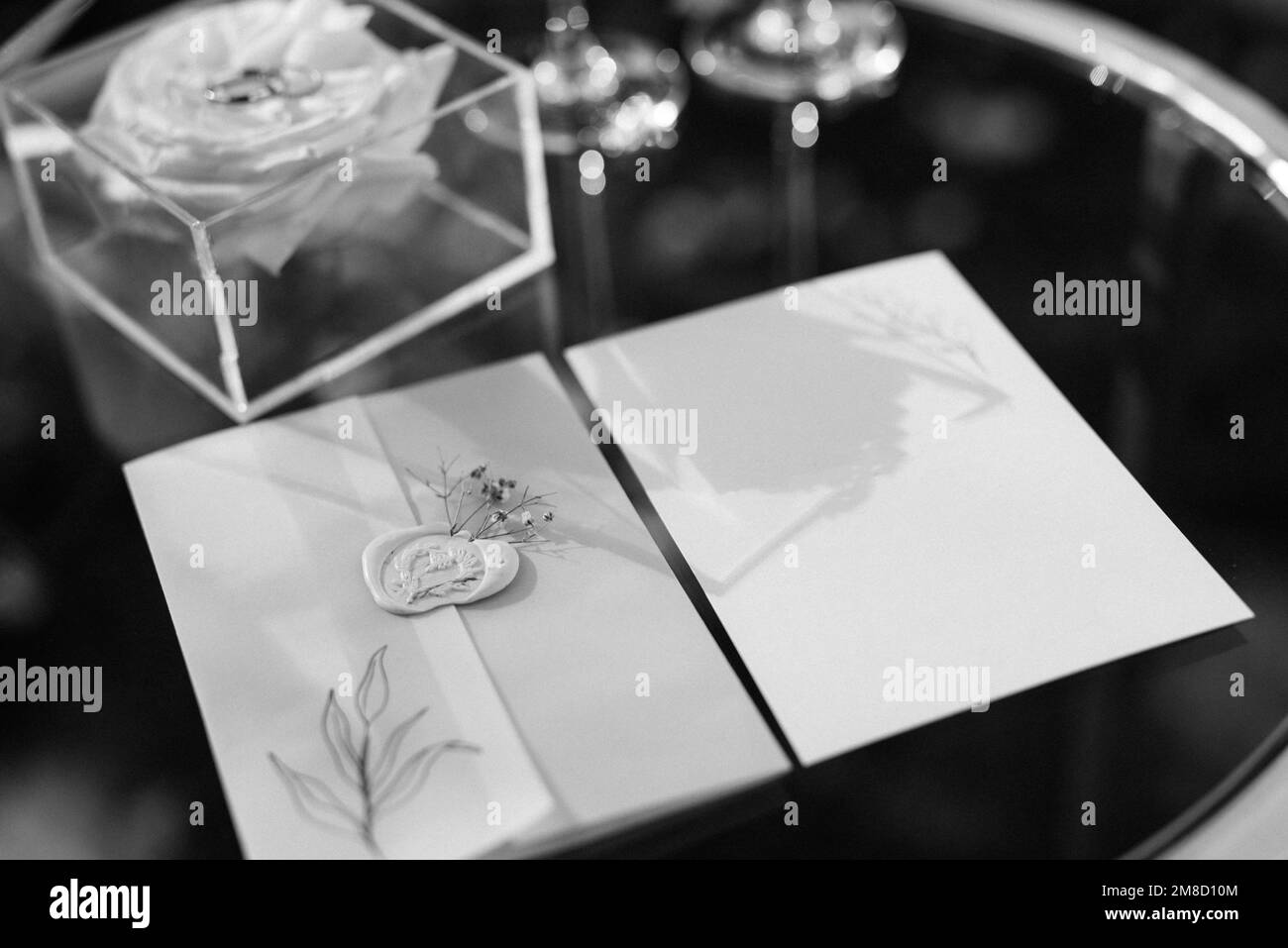 wedding invitation in a blue envelope on a table with green sprigs