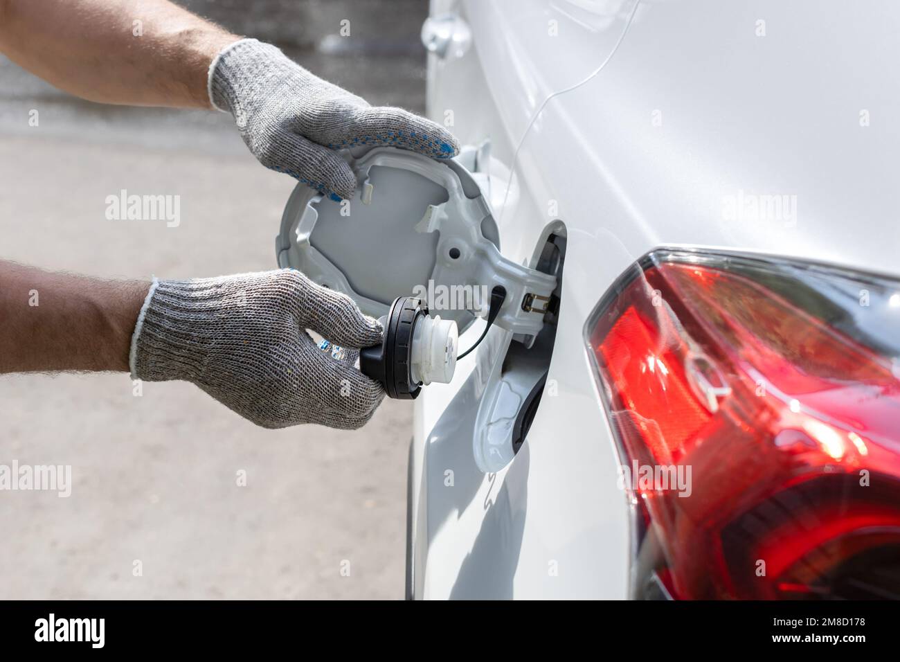man opens the hatch of the gas tank of the car. refueler opens gas tank