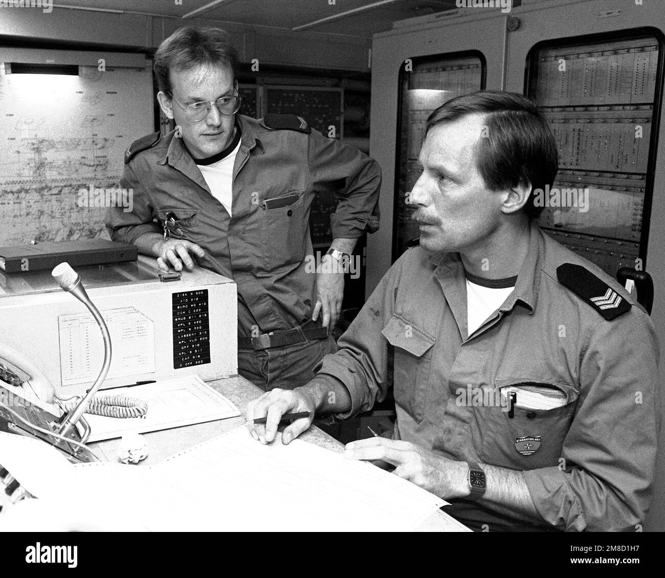 Two sailors check over a computer printout in the technical center ...