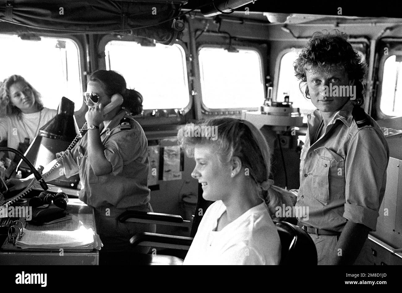 Officers and enlisted personnel tend to their duties in the pilot house
