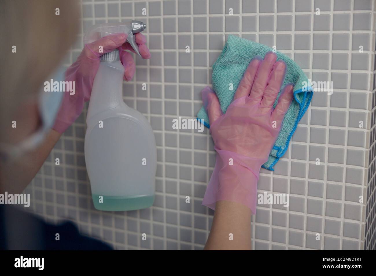 Cleaning lady washing tile wall with detergent and rag. Hygiene, purity