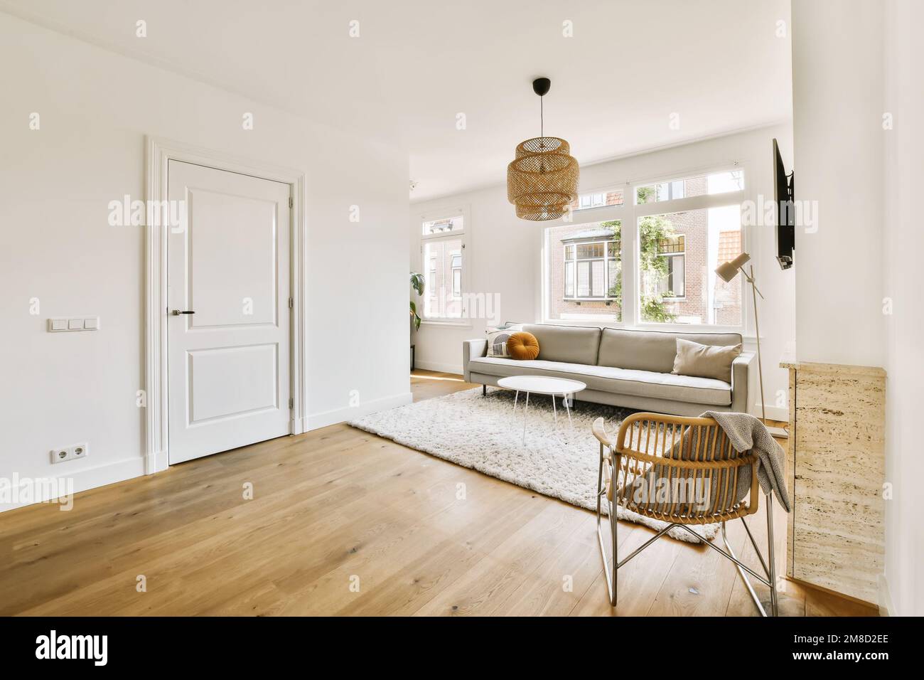a living room with white walls and hardwood flooring, including a grey