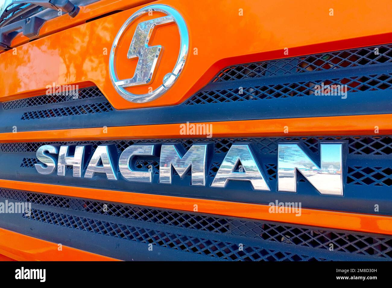 Chinese construction vehicle Shacman brand logo on the orange industrial truck car close up. Stock Photo