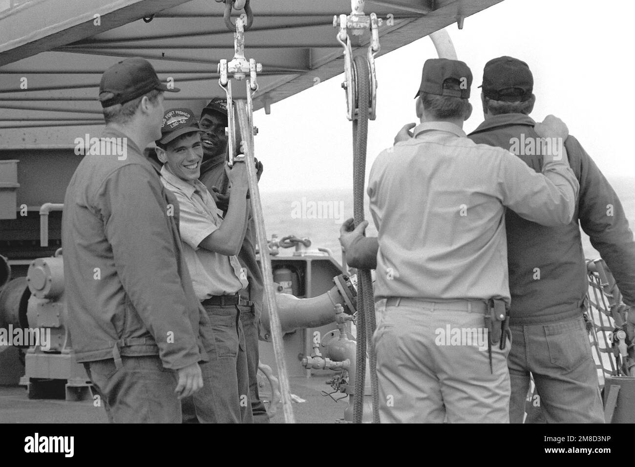 A chief petty officer talks to a group of sailors who are rigging a