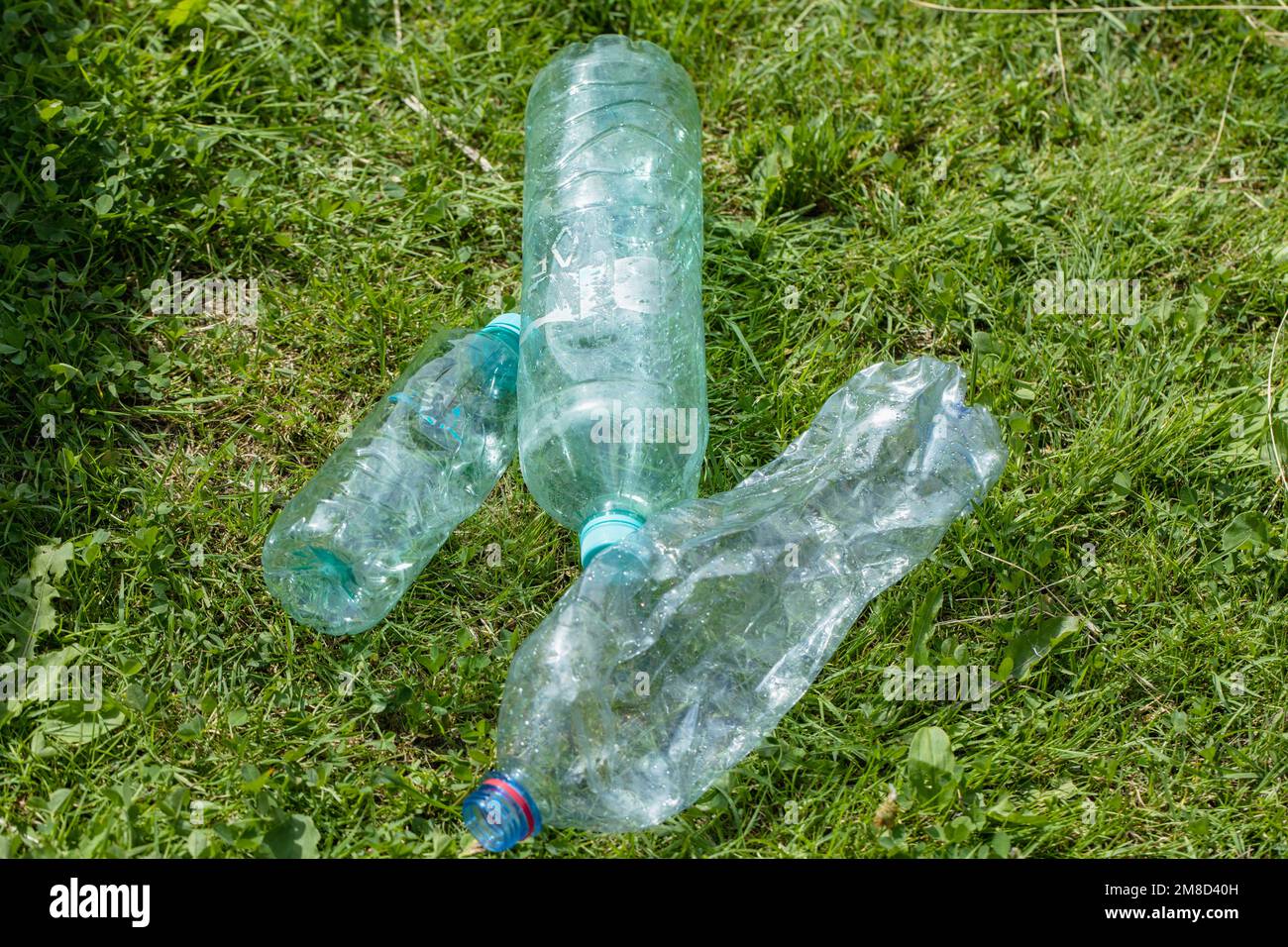 empty plastic bottles are lying on the green lawn Stock Photo