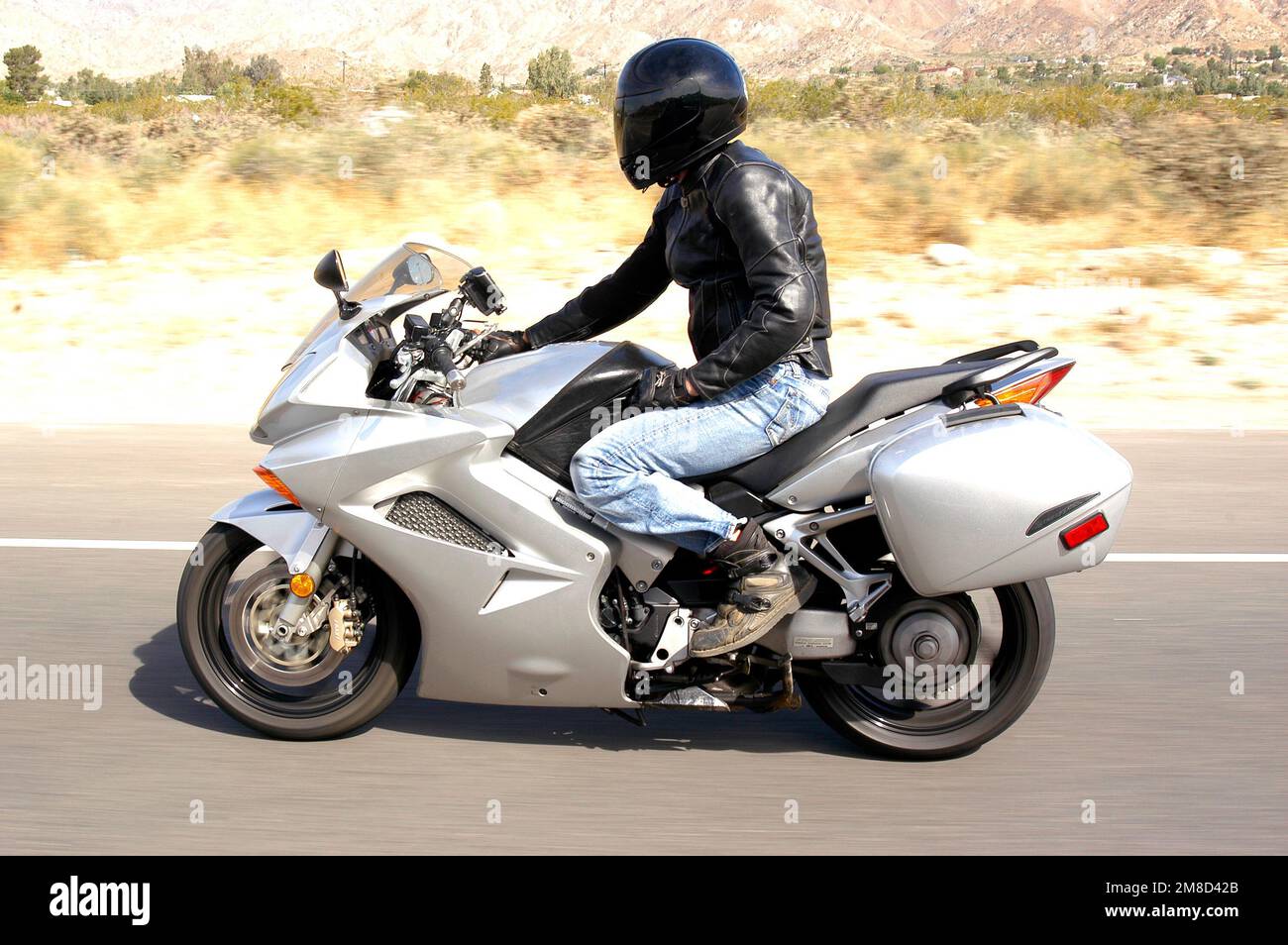 A motorcycle rider races on a highway in the desert surrounding Palm Springs, California Stock