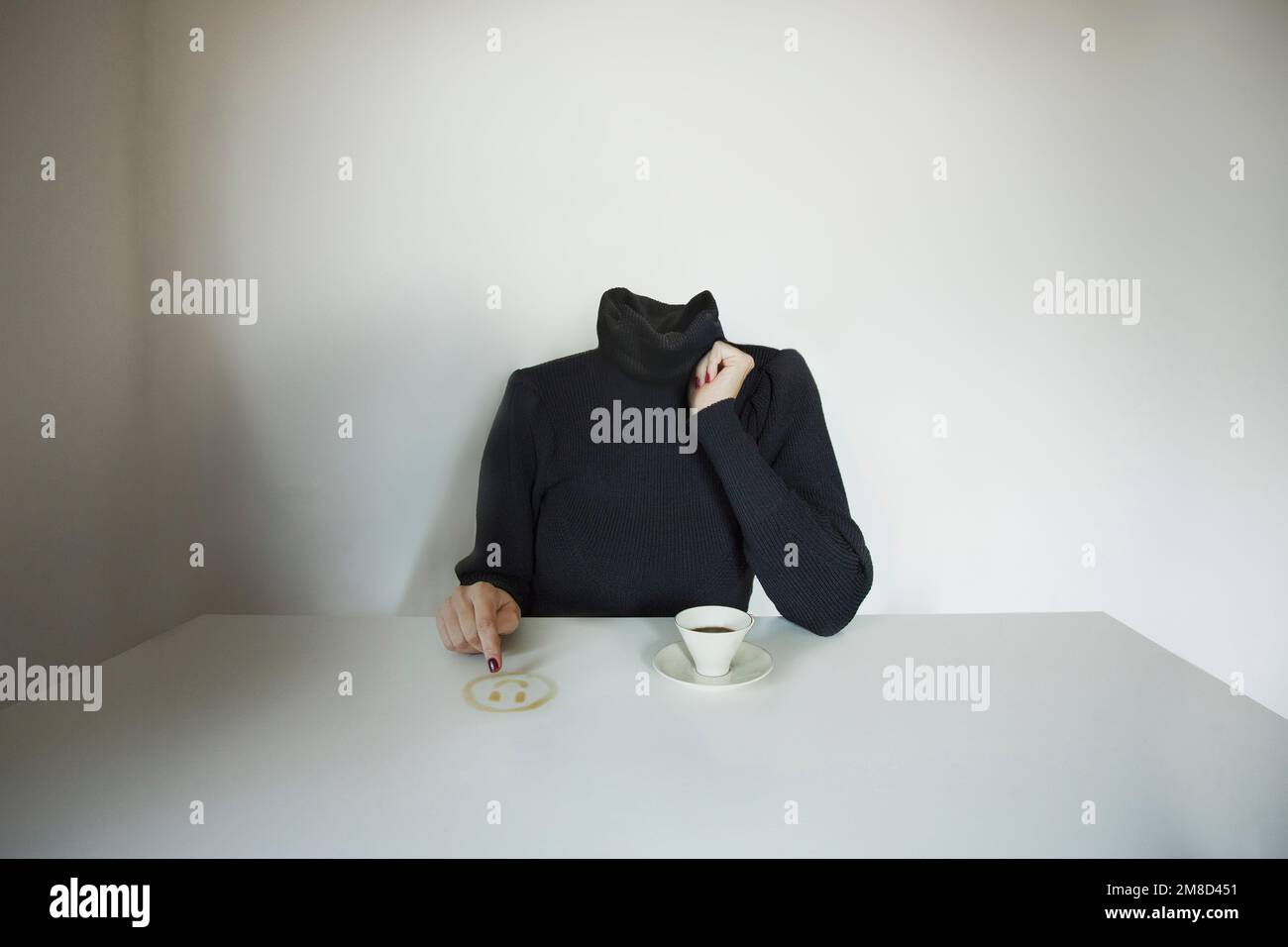 headless surreal woman draws a smile emoji on the table with coffee, concept of communicating one's mood Stock Photo