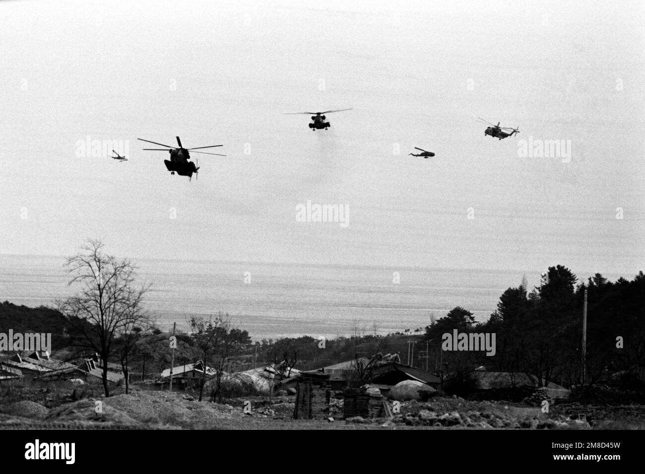 Three Marine Corps CH-53 Sea Stallion helicopters, accompanied by two AH-1 Sea Cobra helicopters, at left and second from right, approach a landing zone near the coast during the combined South Korean/U.S. exercise Team Spirit '90. Subject Operation/Series: TEAM SPIRIT '90 Country: Republic Of Korea (KOR) Stock Photo