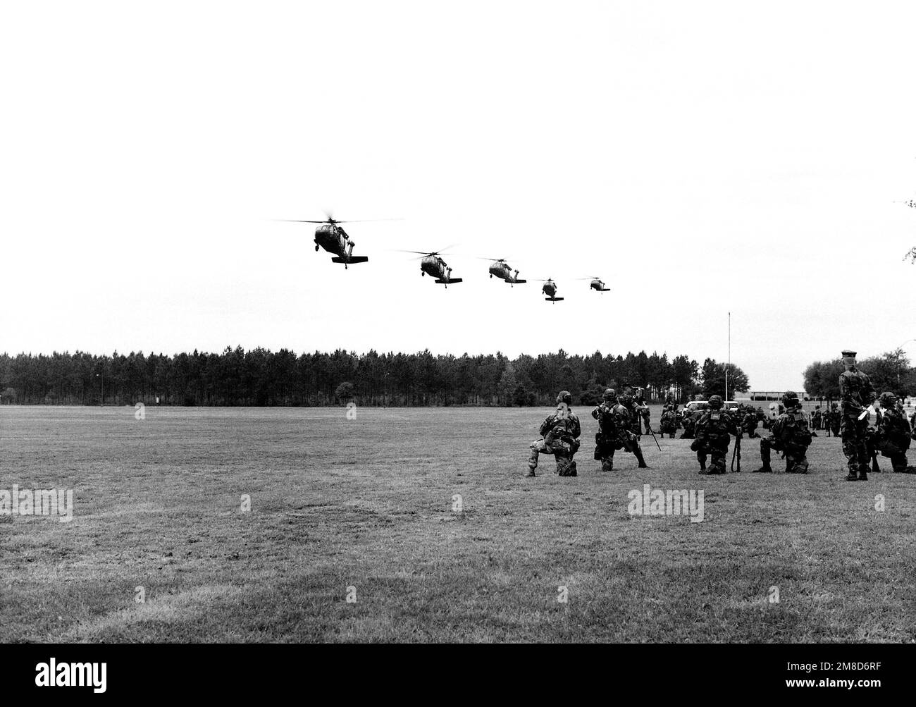 Marines kneel in helicopter teams as they wait for five U.S. Army UH-60A Black Hawk helicopters to touch down in the landing zone. The Marines will be flown to Fort Benning, Georgia, as part of LeaderEx '90. Subject Operation/Series: LEADEREX '90 Base: Marine Corps Logis Base, Albany State: Georgia (GA) Country: United States Of America (USA) Stock Photo