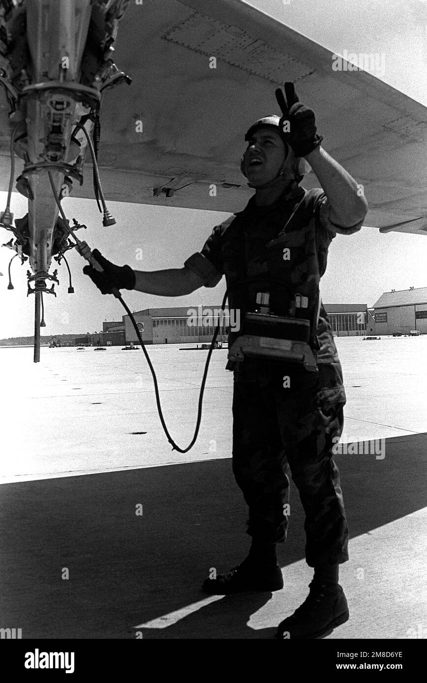 A member of Marine Attack Squadron 224 (VMA-224) signals to the cockpit while using an AN/AWM-54 aircraft firing circuit test set to test a multiple ejector rack (MER) on the wing of an A-6E Intruder aircraft. Base: Mcas, Cherry Point State: North Carolina (NC) Country: United States Of America (USA) Stock Photo