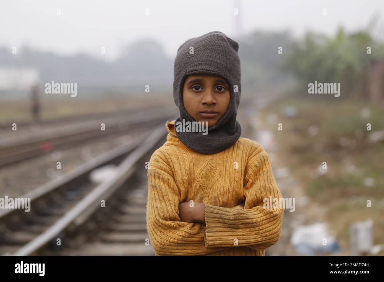 An underprivileged boy poses as he wears winter clothes during a cold