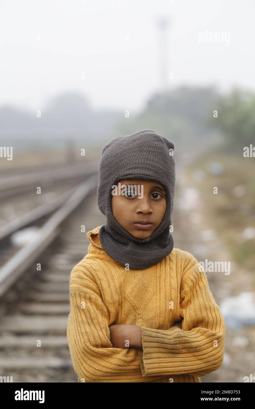 An underprivileged boy poses as he wears winter clothes during a cold