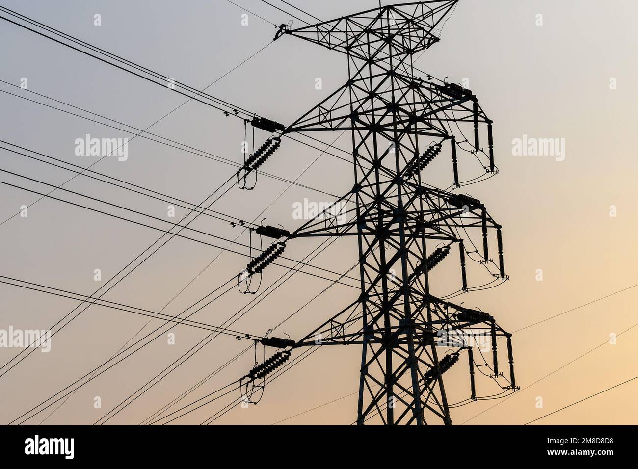 the evening sky with an electric pole with irregular cables which makes ...