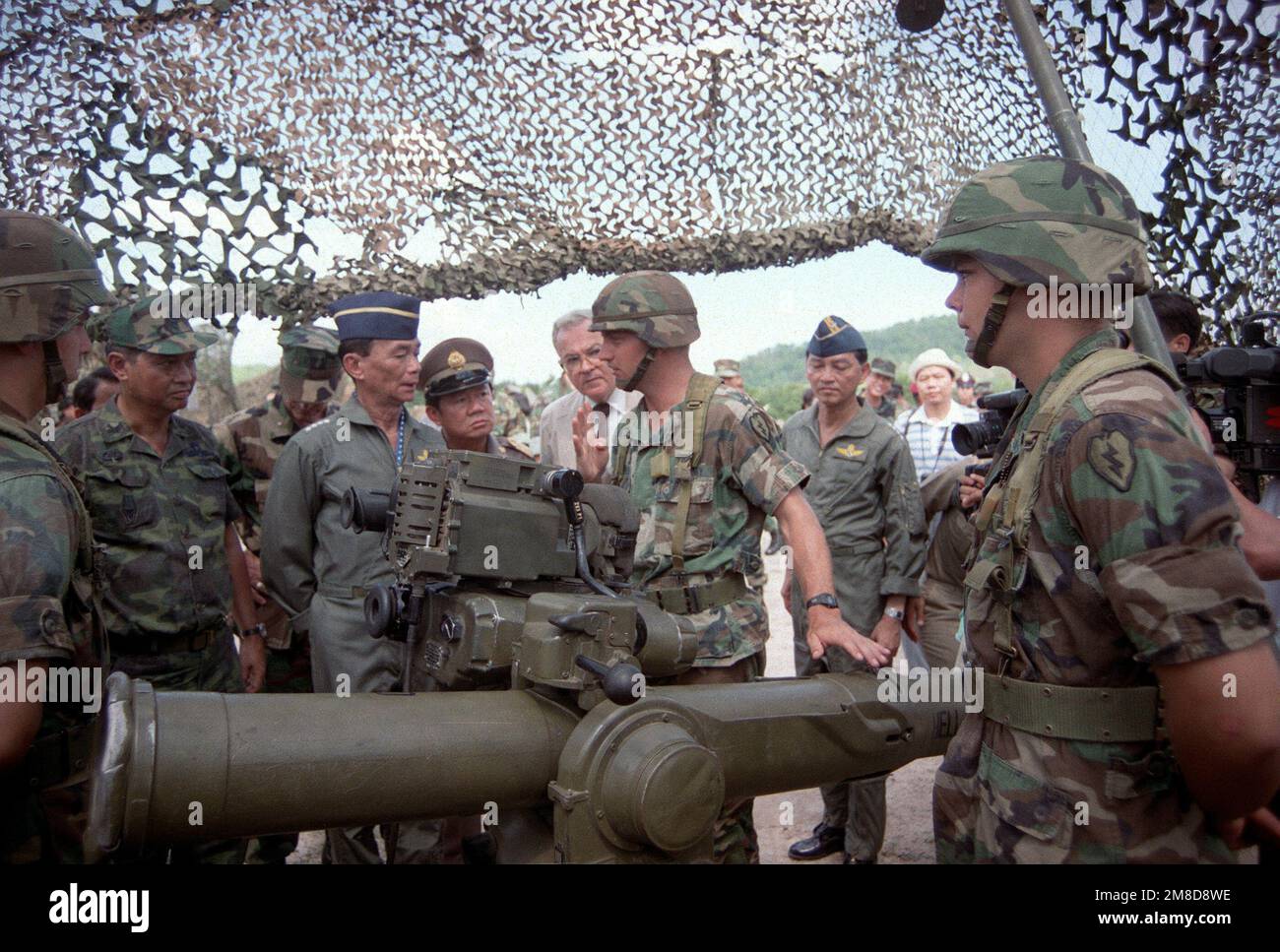 A soldier from 4th Bn., 22nd Inf., 25th Inf. Div. (Light), explains the TOW tube-launched, optically tracked, wire-guided heavy anti-tank weapon to GEN Sundhara Kongsompong, Supreme Commander, Royal Thai Armed Forces, and U.S. Ambassador to Thailand Daniel A. O'Donohue following the opening ceremonies for the combined Thai/U.S. exercise Cobra Gold '90. Subject Operation/Series: COBRA GOLD '90 Base: Chon Buri Country: Thailand (THA) Stock Photo