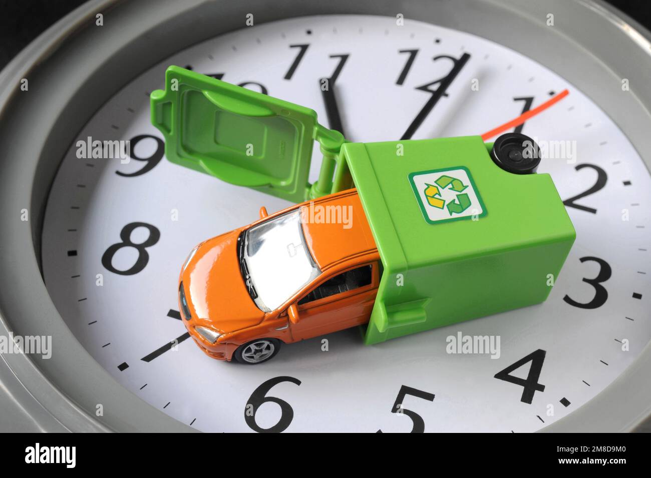 MODEL CAR IN RECYCLING BIN ON CLOCK FACE RE RECYCLING CARS ELECTRIC EMISSIONS DRIVERS ELECTRIC FUEL DIESEL PETROL TIME RUNNING OUT ETC  UK Stock Photo