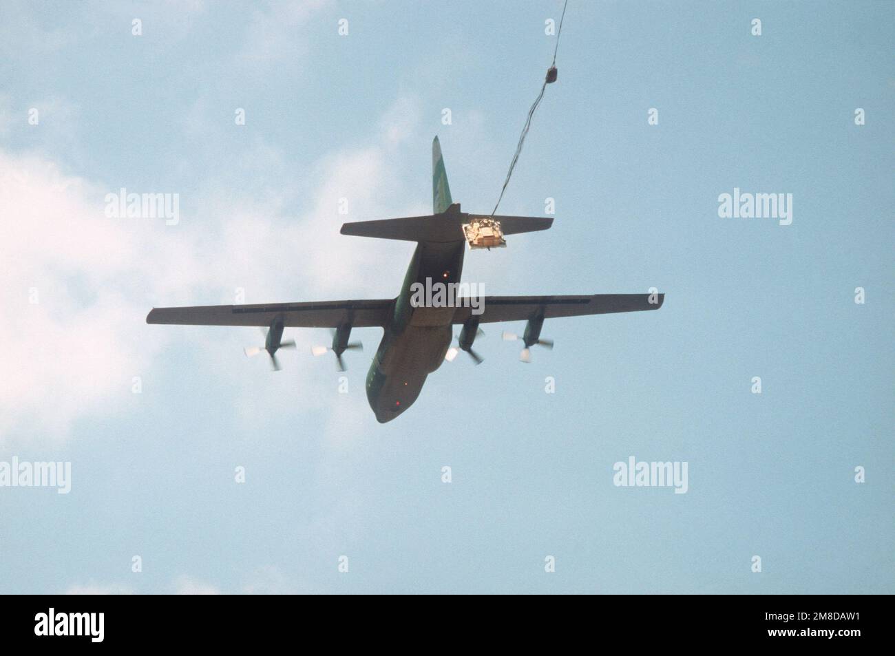 A C-130 Hercules transport aircraft drops simulated heavy equipment on ...