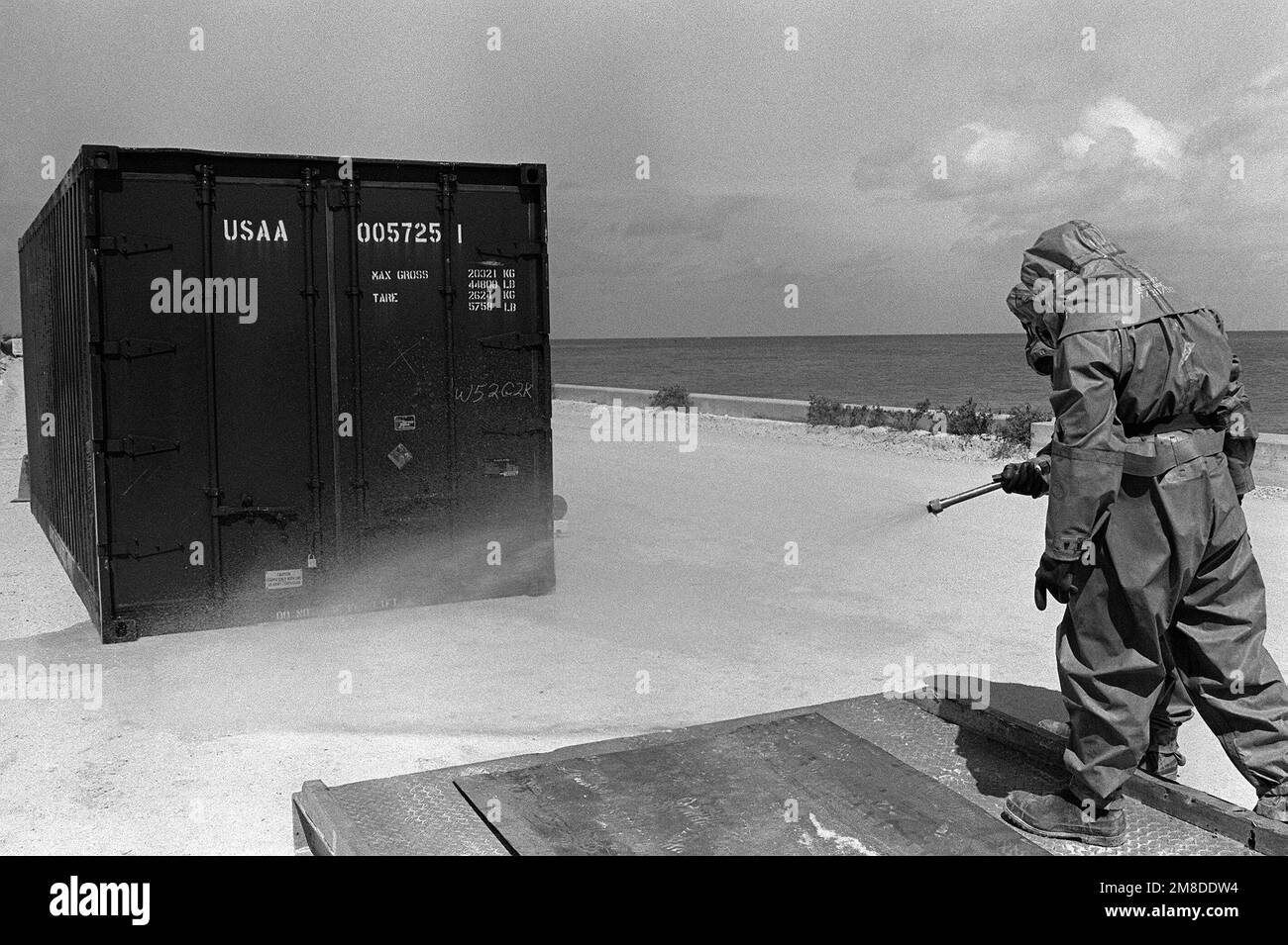Two soldiers from the 71st Chemical Regiment, 25th Infantry Division (Light), spray a decontamination solution on and around a container express (CONEX) box used to store chemical munitions. The soldiers are taking part in an exercise designed to test the unit's ability to detect and mitigate a chemical leak. Base: US Army Chemical Activity Country: Johnston Atoll Stock Photo