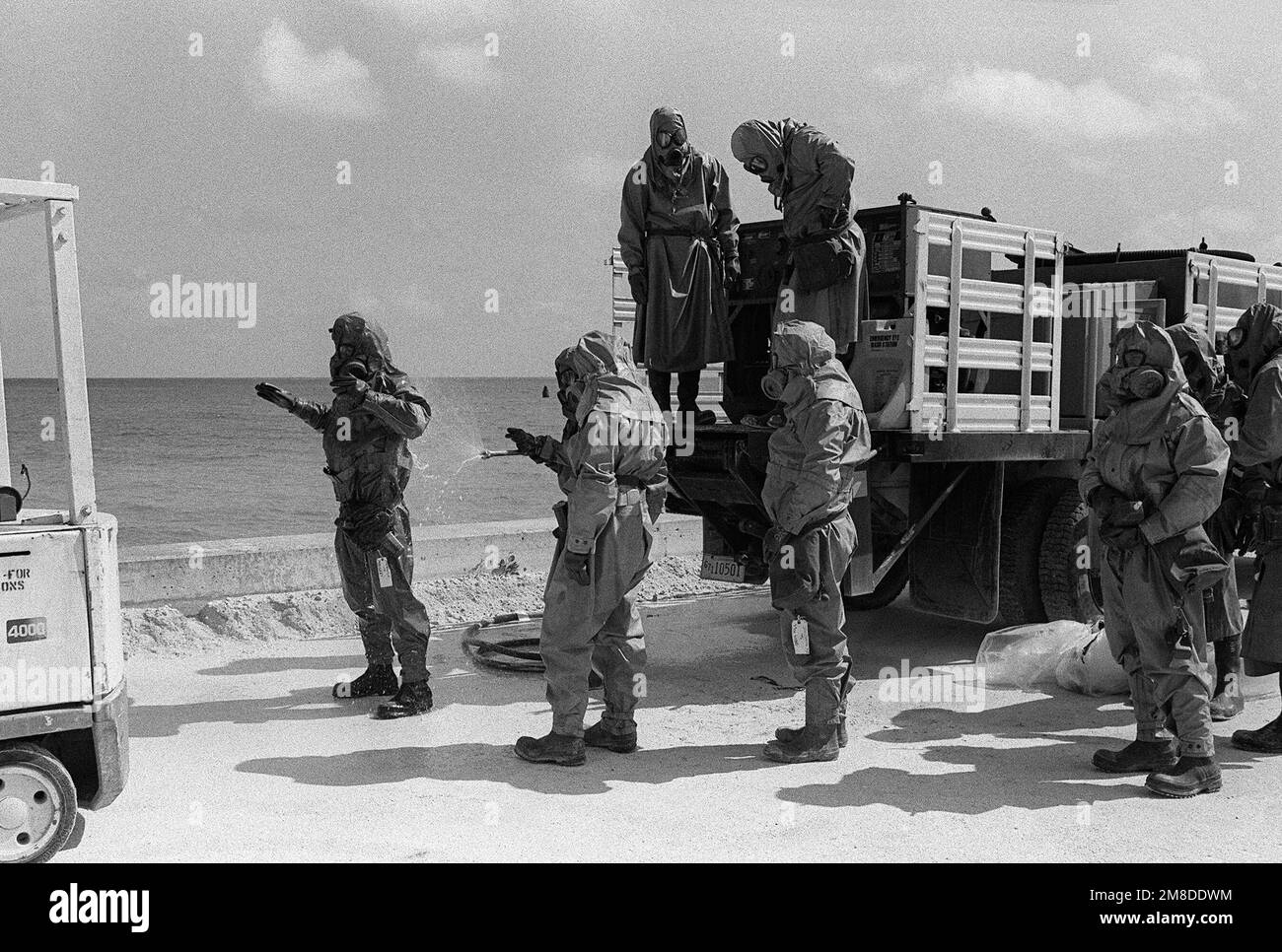 Dressed in full protective gear soldiers from the 71st Chemical Regiment, 25th Infantry Division (Light), line up to be sprayed with a decontamination solution near the conclusion of an exercise designed to test the unit's ability to detect and mitigate a chemical leak. Base: US Army Chemical Activity Country: Johnston Atoll Stock Photo