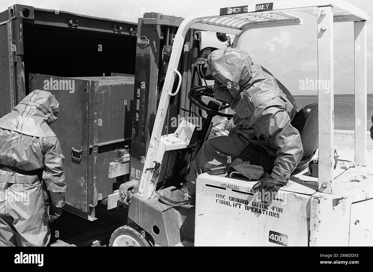 Wearing full protective gear, members of the 71st Chemical Regiment, 25th Infantry Division (Light), unload a sealed container of chemical munitions from a container express (CONEX) box during an exercise designed to test the unit's ability to detect and mitigate a chemical leak. Base: US Army Chemical Activity Country: Johnston Atoll Stock Photo