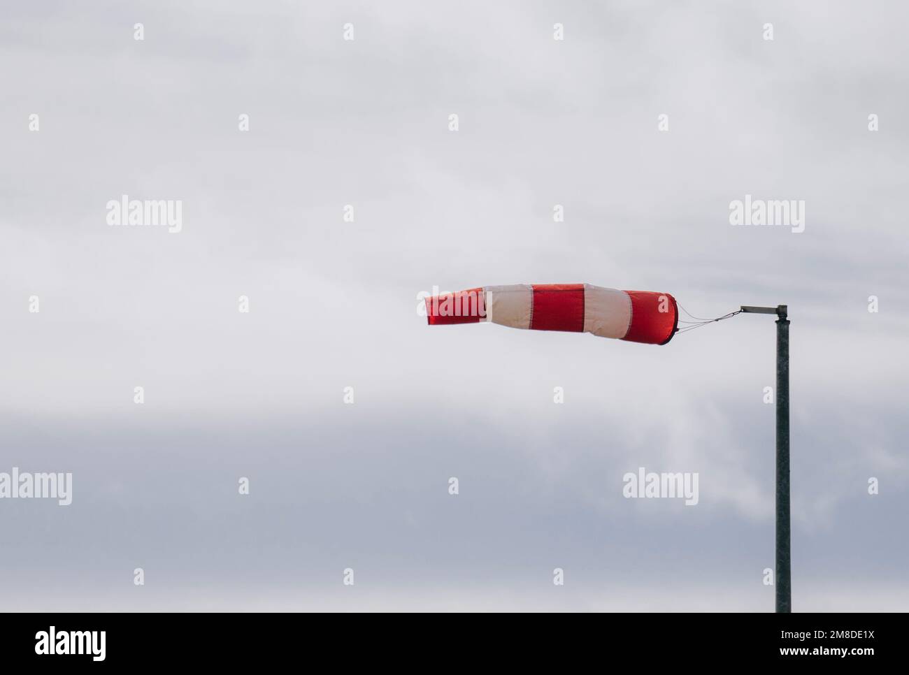 Frayed windsock in moderate wind against blue sky with copy space. Stock Photo
