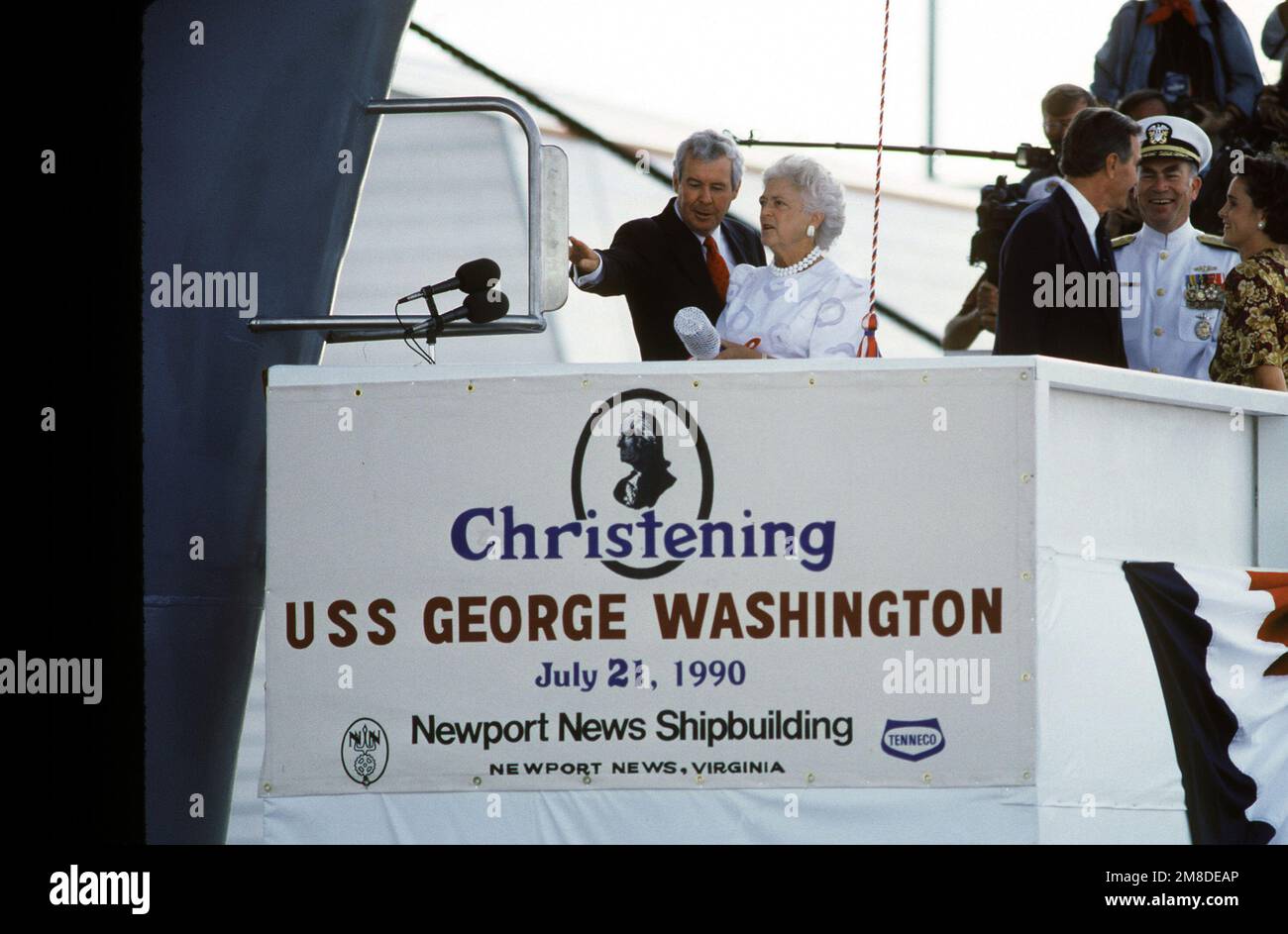 Edward J. Campbell, President of Newport News Shipbuilding Company, shows Barbara Bush, ship's sponsor, where to break the champagne bottle prior to the christening ceremony of the nuclear-powered aircraft carrier GEORGE WASHINGTON (CVN 73) at Newport News Shipbuilding Company. Also present on the speakers platform are President George H.W. Bush, principal speaker; Admiral (ADM) Frank B. Kelso II, CHIEF of Naval Operations, and Mrs. Dorothy LeBlond, matron of honor. As the sixth ship of its class, the GEORGE WASHINGTON represents the most technologically advanced Nimitz class carrier. Base: Ne Stock Photo