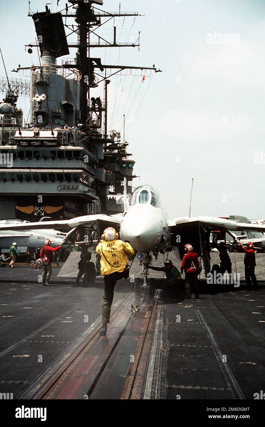 A Petty Officer Kicks The Launch Shuttle Aft To A Waiting Catapult Crewman As A Fighter Squadron