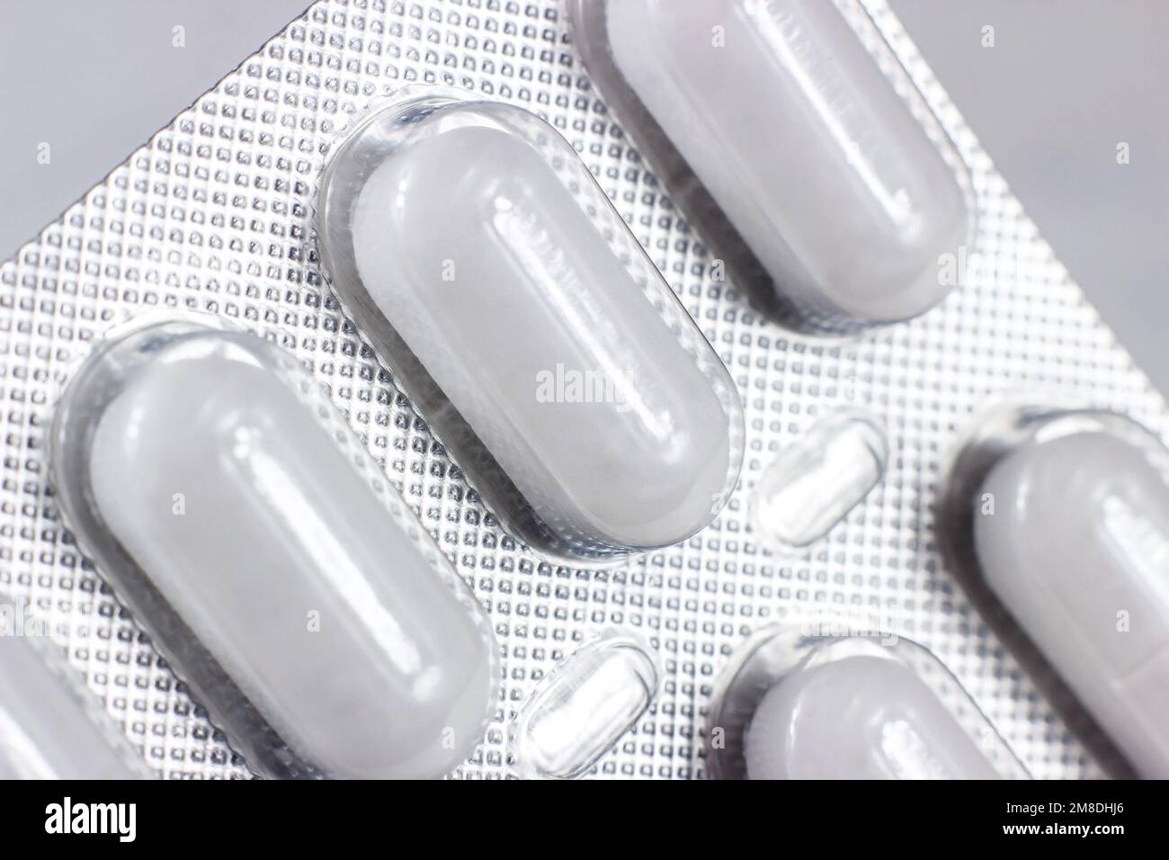 Silver and white foil blister pack with medical pills on light background close up. Stock Photo
