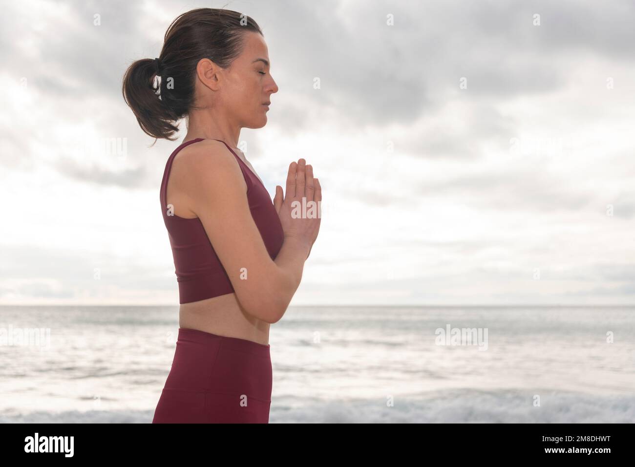woman praying and meditating outdoors by seaside. Self care and mindfulness, menthal health. Awakening in morning. Stock Photo