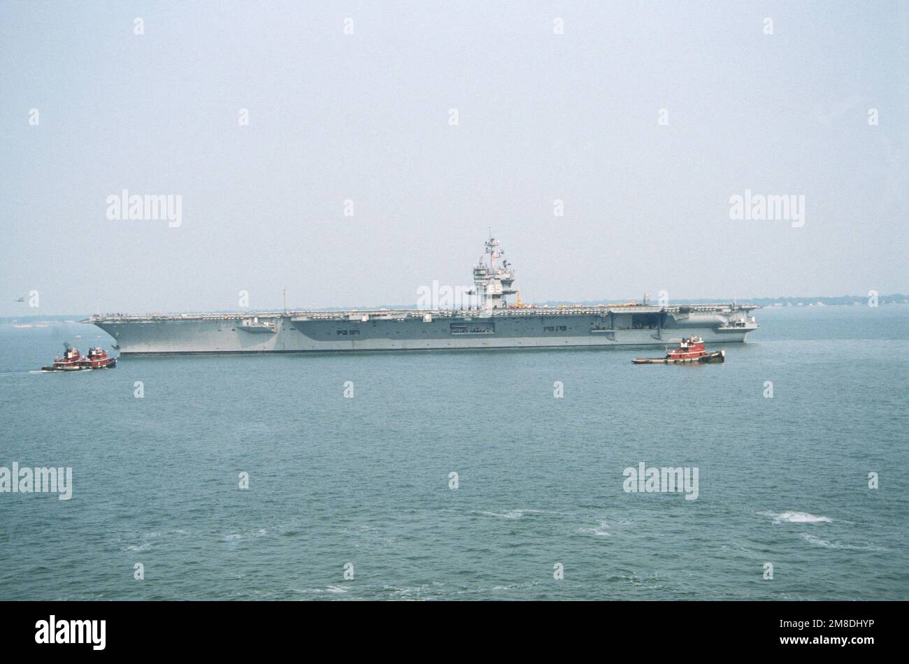 Tug boats stand by as the nuclearpowered aircraft carrier USS