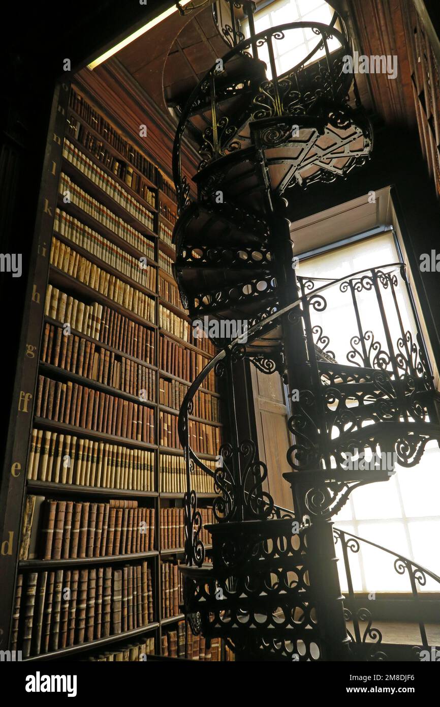 Spiral Staircase, bookcase, at Trinity College Library adjacent to bookshelves of old books, College Green, Dublin D02, Eire, Ireland Stock Photo