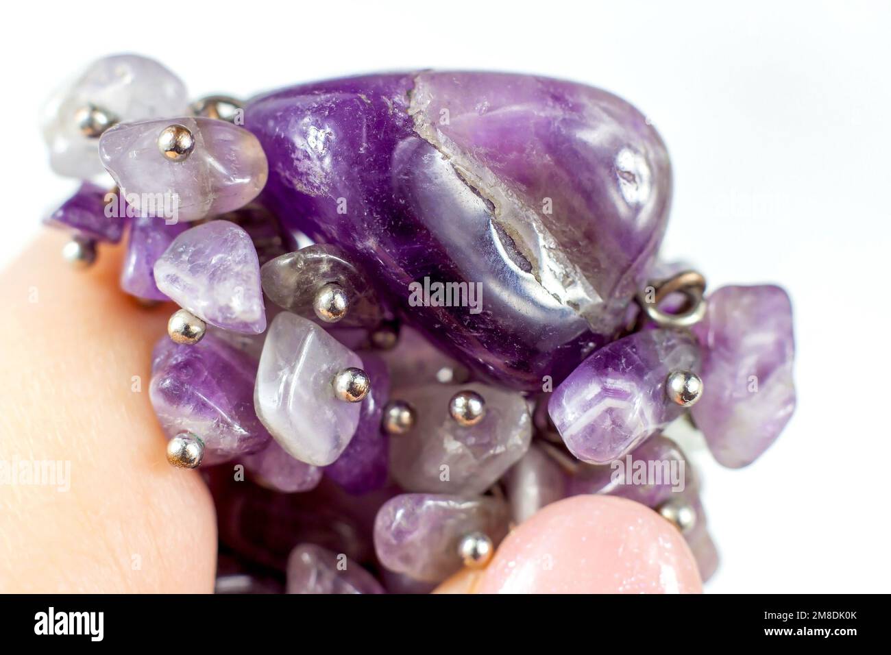 Bright transparent violet amethyst crystal gems in the hand on light background close up. Stock Photo