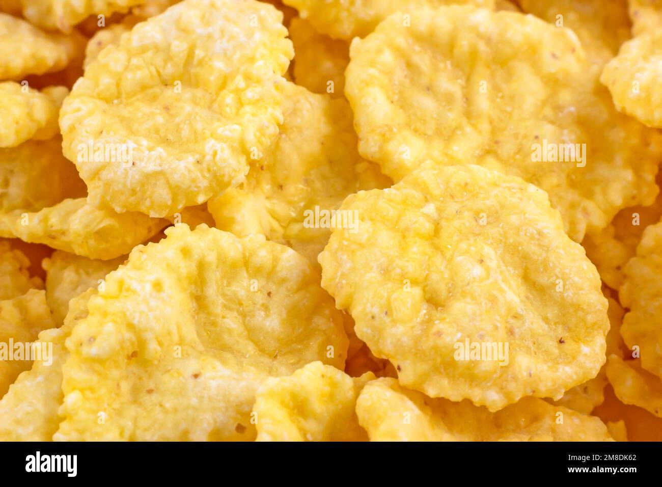 Bright yellow tasty sugar crunchy cornflakes for breakfast as a texture close up. Stock Photo