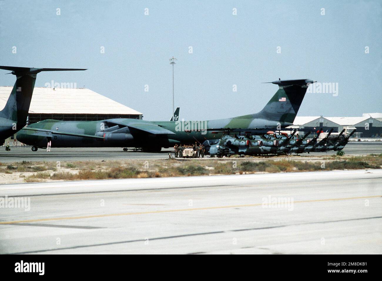 C-141B Starlifter aircraft and AH-1 Sea Cobra helicopters stand on the ...