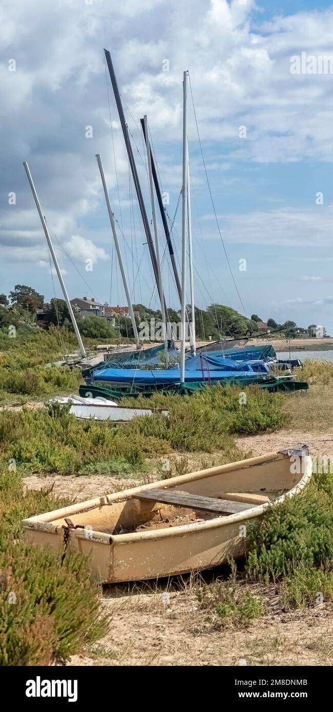 WEST MERSEA, ESSEX, UK - AUGUST 31, 2018:  Upright panorama of dinghies pulled up on the Beach along the River Blackwater Stock Photo