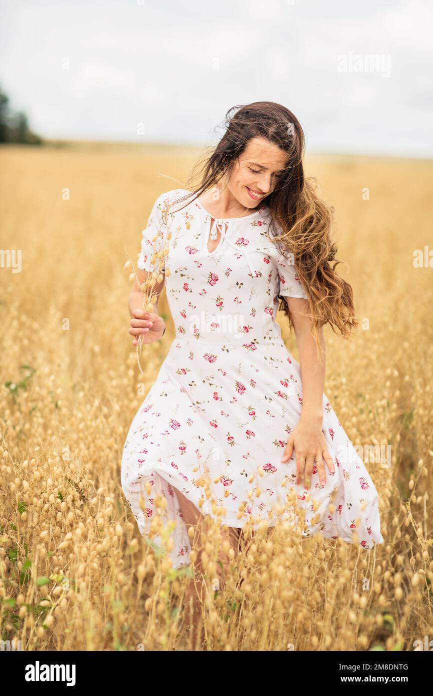 Young woman in white midi dress walking across the field Stock Photo ...