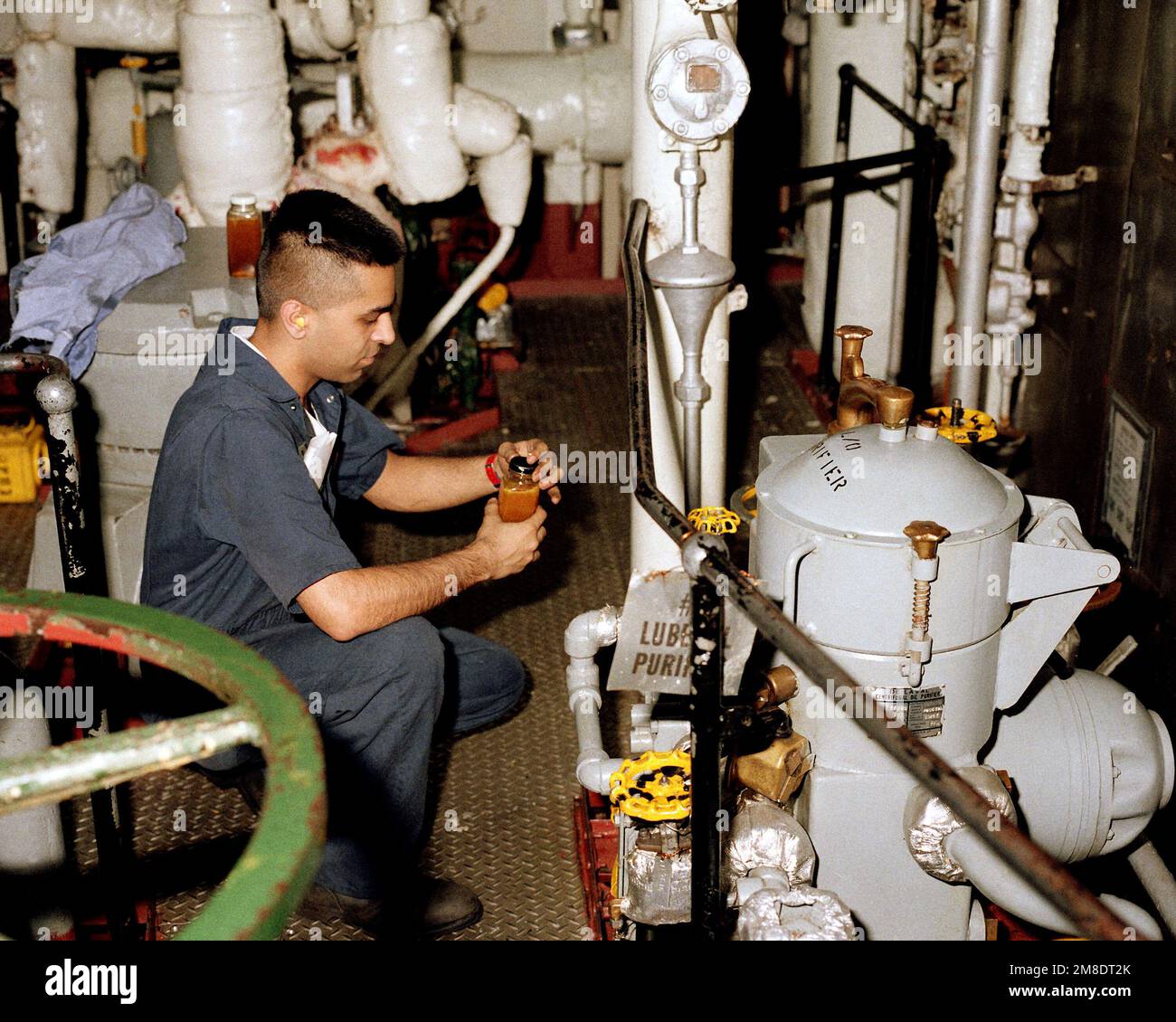 A crew member takes a sample from an oil purifier aboard the aircraft carrier USS JOHN F. KENNEDY (CV 67). Base: USS John F. Kennedy (CV 67) Stock Photo