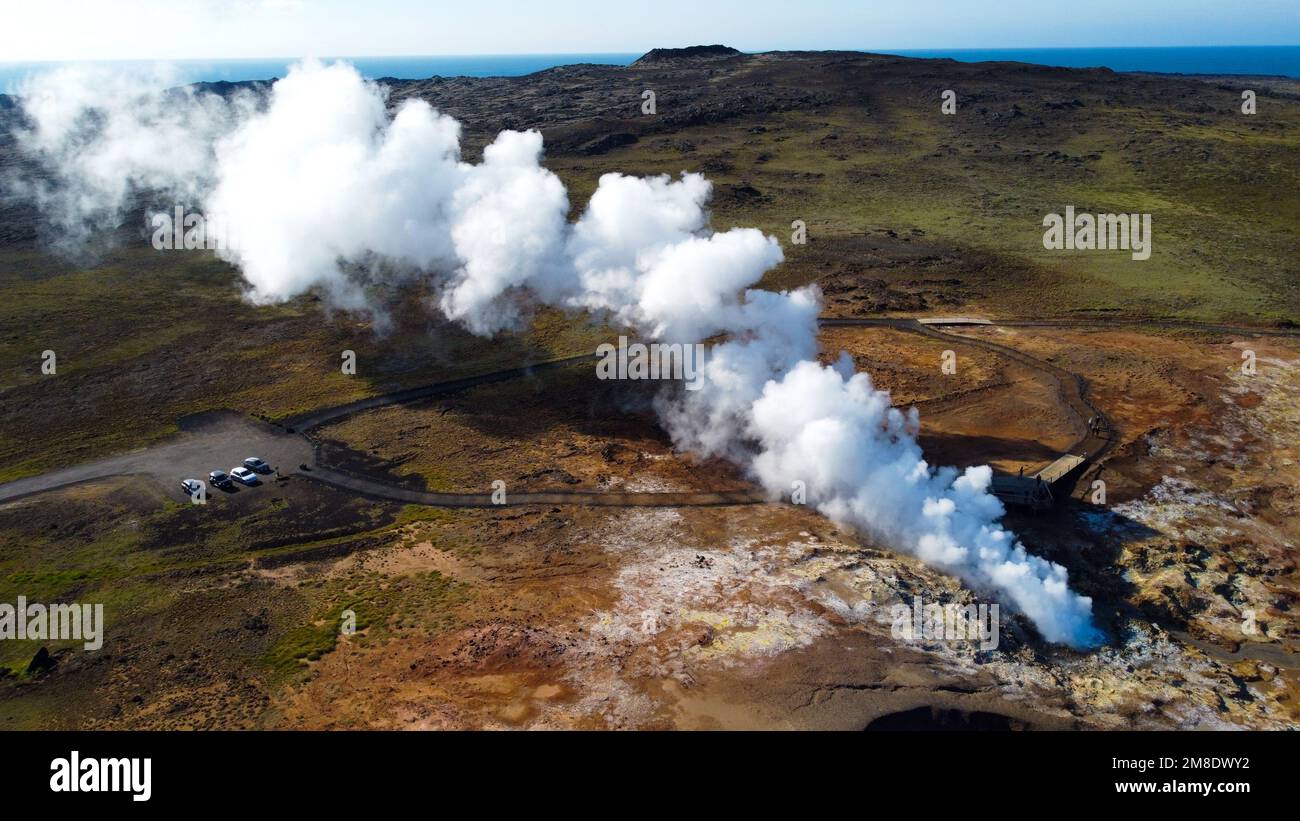 An aerial view of hot steam coming out of geothermal geyser surrounded by beautiful landscapes Stock Photo