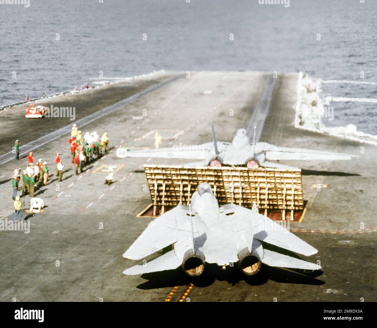 Flight deck crew members stand by as a Fighter Squadron 114 (VF114) F