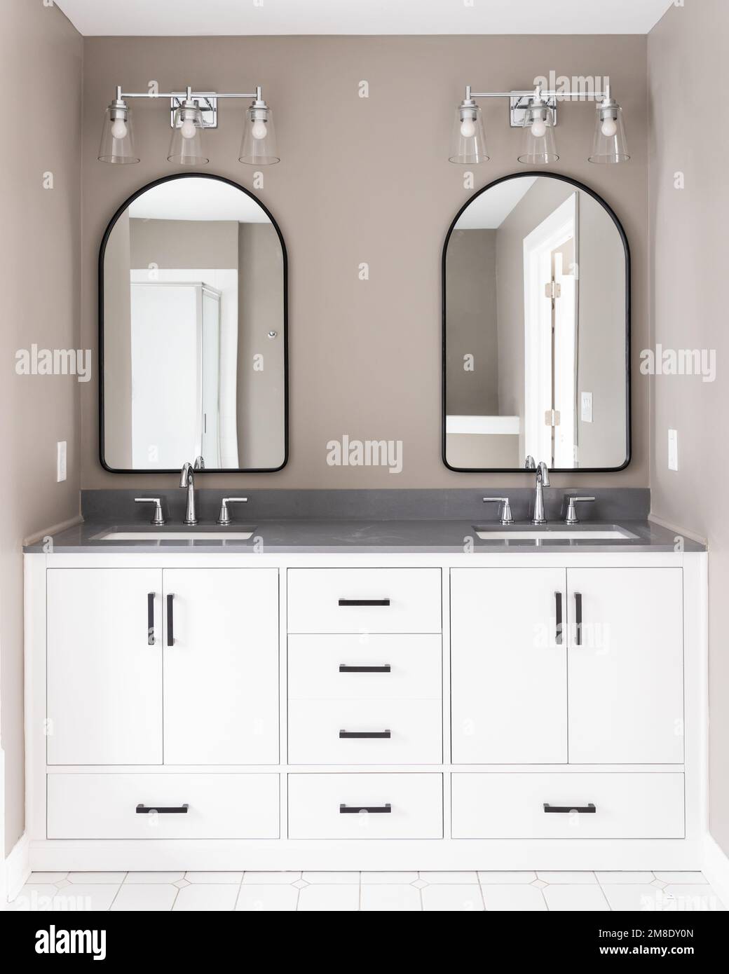 A bathroom with a white vanity and black hardware, chrome faucets on a