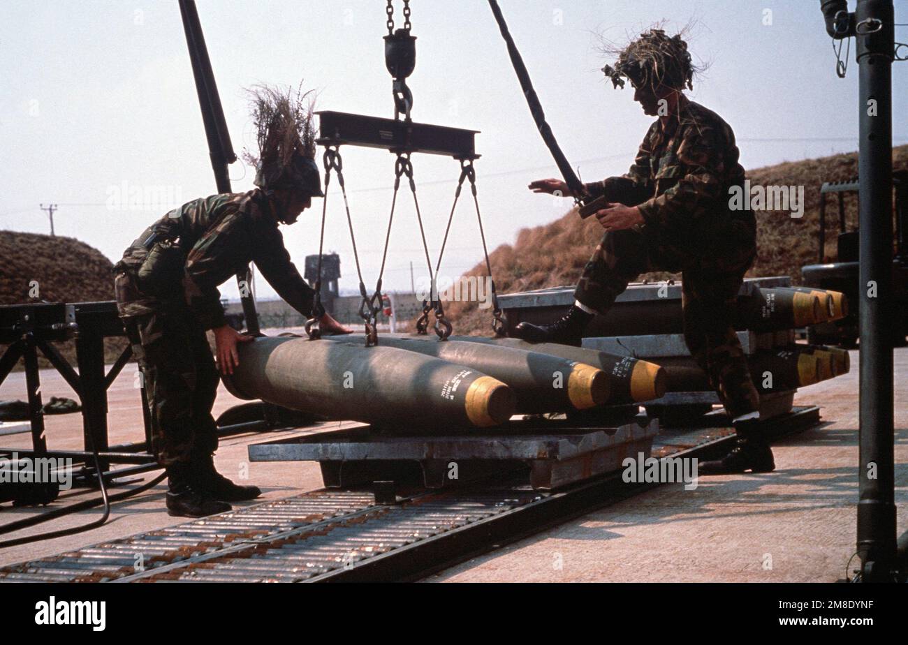 SENIOR AIRMAN Phillip Ruddock, left, and AIRMAN 1ST Class Thomas Hearl of the 6151st Consolidated Aircraft Maintenance Squadron (6151st CAMS) lower three Mark 82 500-pound bombs onto a pallet during the joint South Korean/United States exercise TEAM SPIRIT '89. Subject Operation/Series: TEAM SPIRIT '89 Base: Suwon Air Base Country: Korea Stock Photo