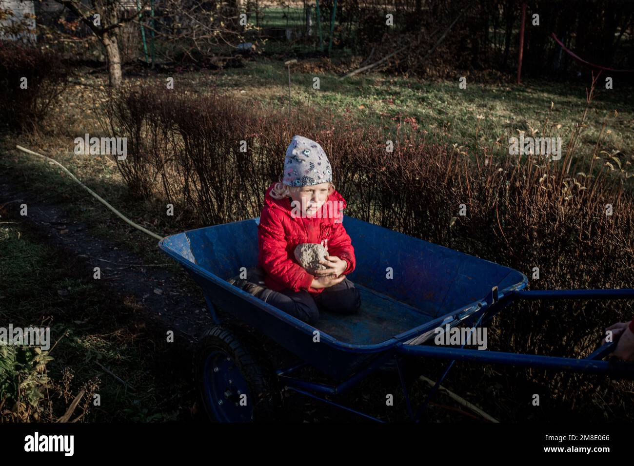 children on a garden cart to the nature in the spring garden. Stock Photo