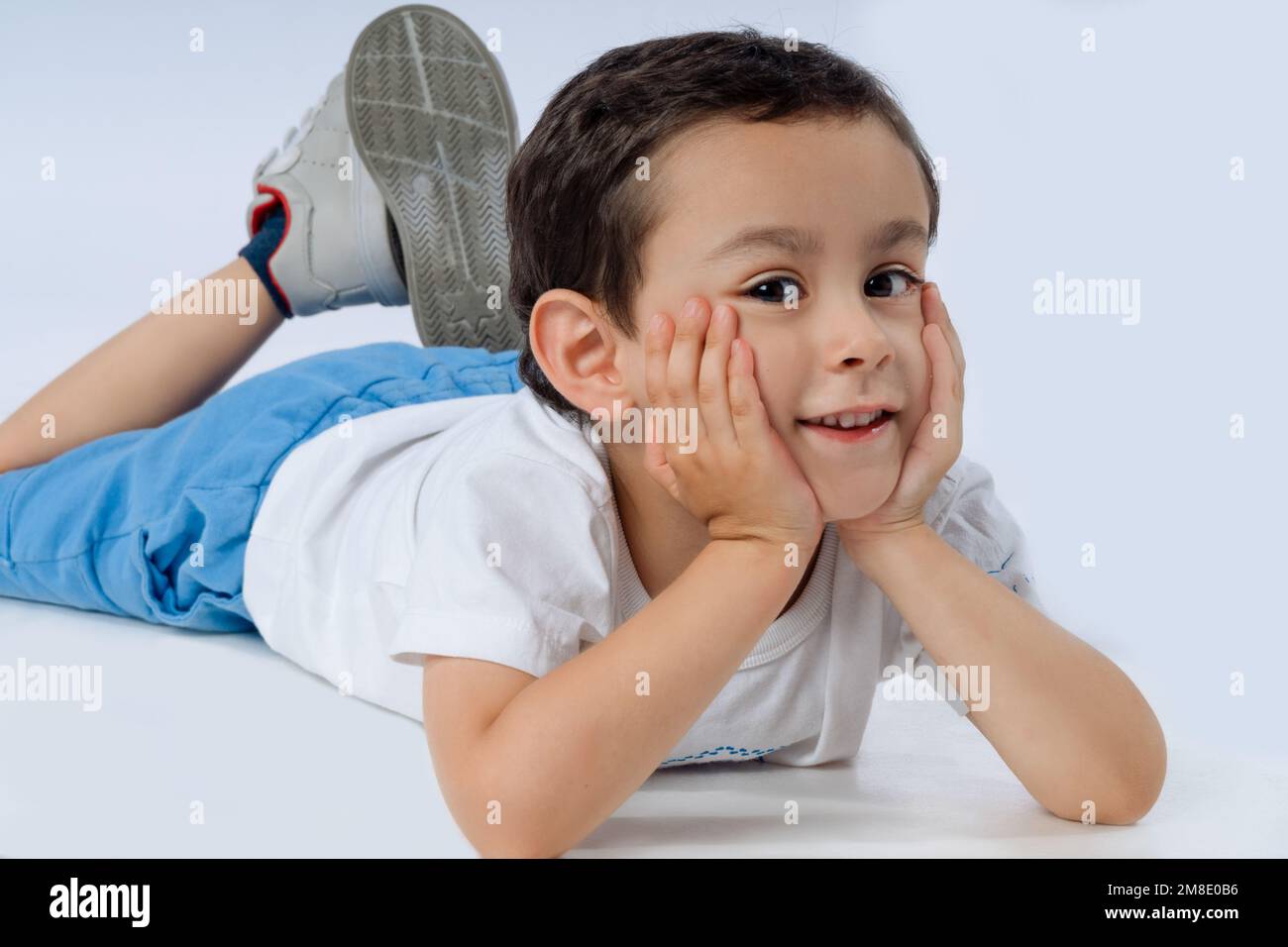 Little boy is lying on the floor, smiling and looking at the camera